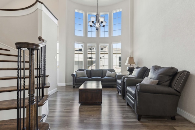 living room featuring a towering ceiling, dark hardwood / wood-style floors, and an inviting chandelier