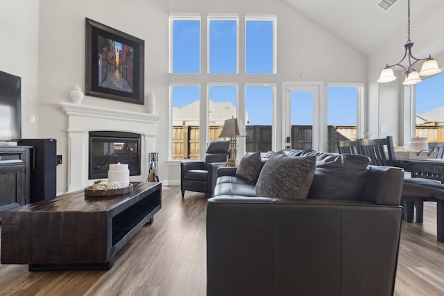 living room with a towering ceiling, wood-type flooring, and a notable chandelier