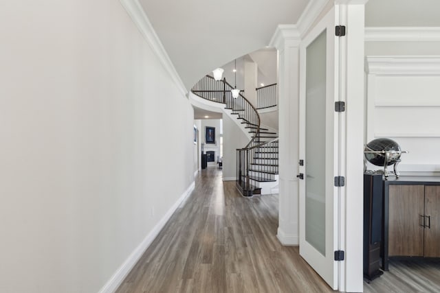 corridor featuring wood-type flooring, crown molding, and a notable chandelier