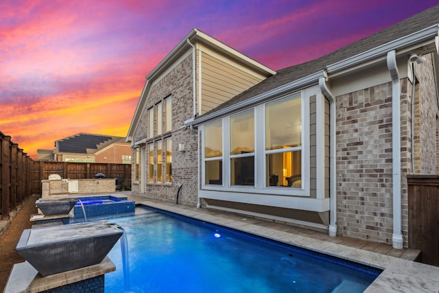 pool at dusk with an in ground hot tub