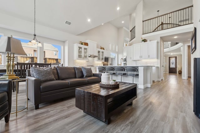 living room featuring light wood-type flooring and a towering ceiling