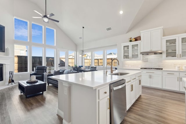 kitchen featuring sink, stainless steel dishwasher, decorative backsplash, a center island with sink, and white cabinets