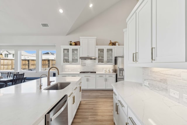 kitchen featuring sink, white cabinets, vaulted ceiling, and appliances with stainless steel finishes