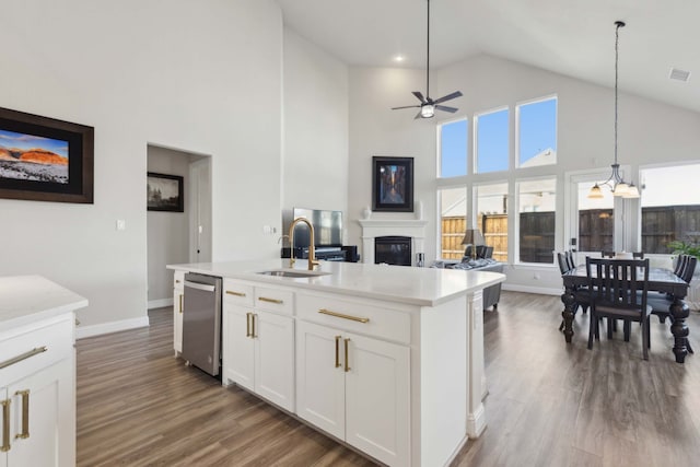 kitchen with stainless steel dishwasher, ceiling fan, a kitchen island with sink, white cabinetry, and hanging light fixtures