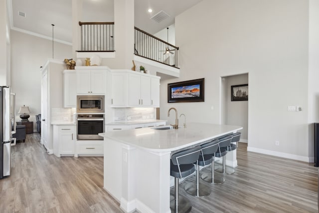 kitchen with a breakfast bar, white cabinetry, an island with sink, and appliances with stainless steel finishes