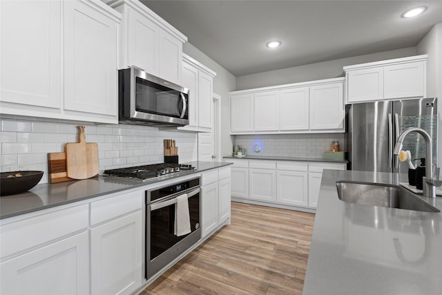 kitchen with appliances with stainless steel finishes, backsplash, white cabinetry, and sink