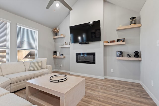 living room featuring ceiling fan, light hardwood / wood-style floors, and vaulted ceiling