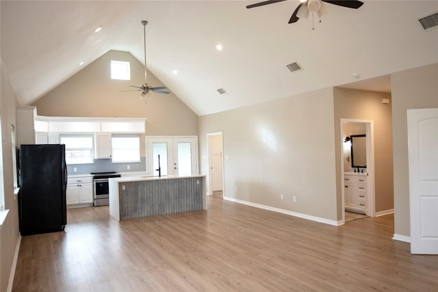 kitchen featuring a center island, black fridge, stainless steel range, and white cabinets