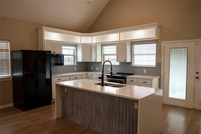 kitchen with sink, plenty of natural light, an island with sink, white cabinets, and black appliances