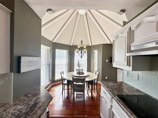 dining room featuring lofted ceiling, dark wood-type flooring, and an inviting chandelier