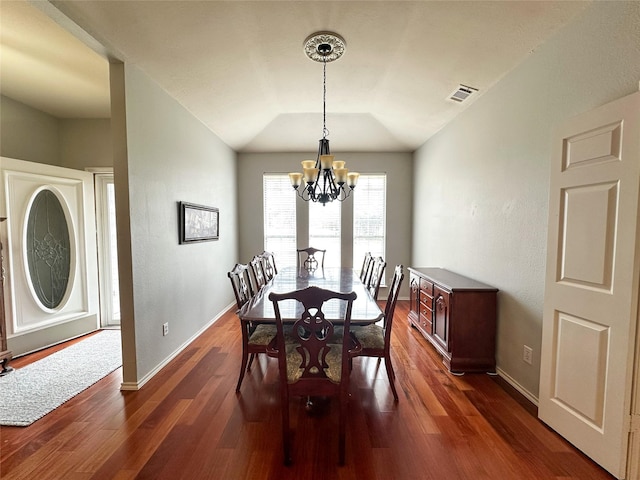 dining area with dark hardwood / wood-style floors, vaulted ceiling, and an inviting chandelier