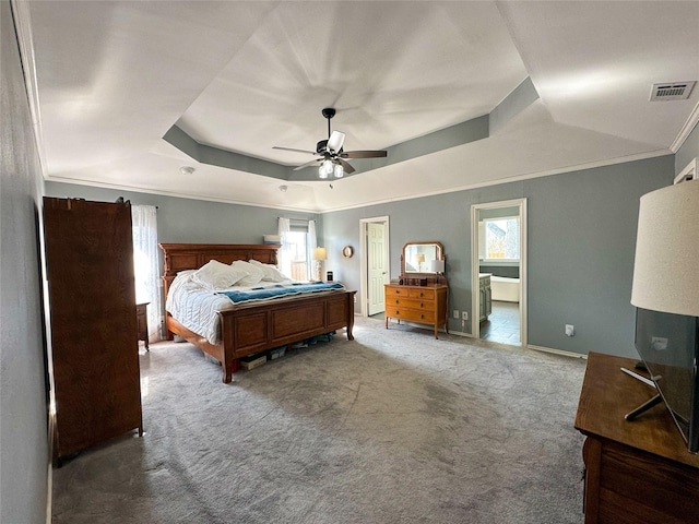 carpeted bedroom featuring multiple windows, a tray ceiling, ceiling fan, and ornamental molding