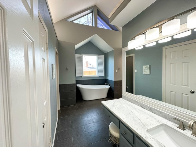 bathroom with a wealth of natural light, vanity, a bath, and vaulted ceiling