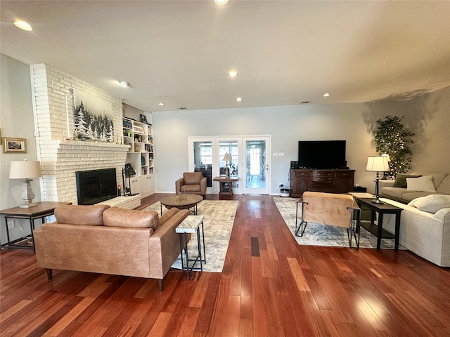 living room with a brick fireplace, dark hardwood / wood-style floors, and built in features