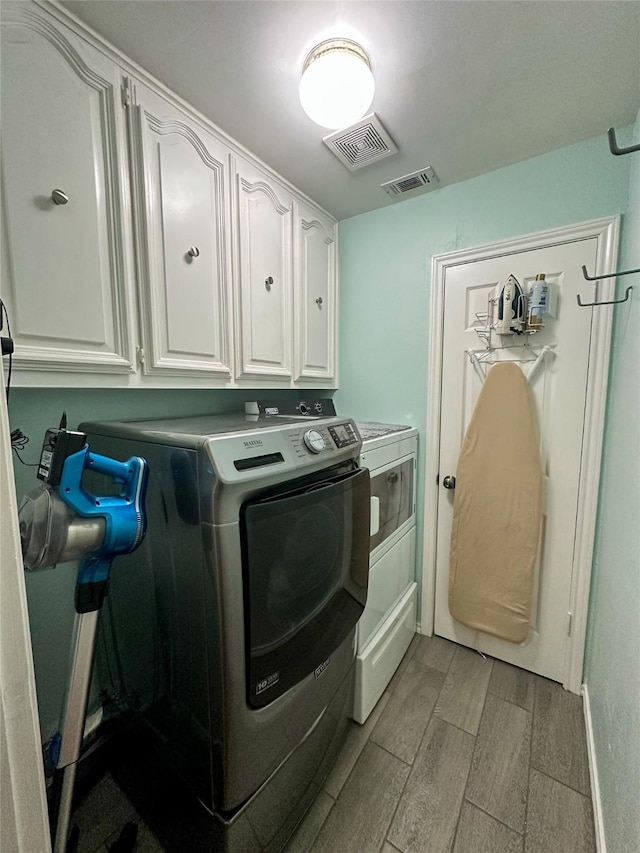 laundry room featuring washer and clothes dryer and cabinets