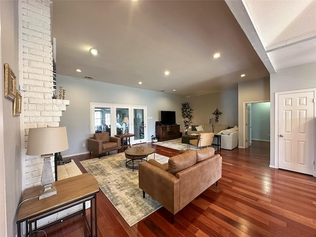 living room featuring a brick fireplace and dark wood-type flooring