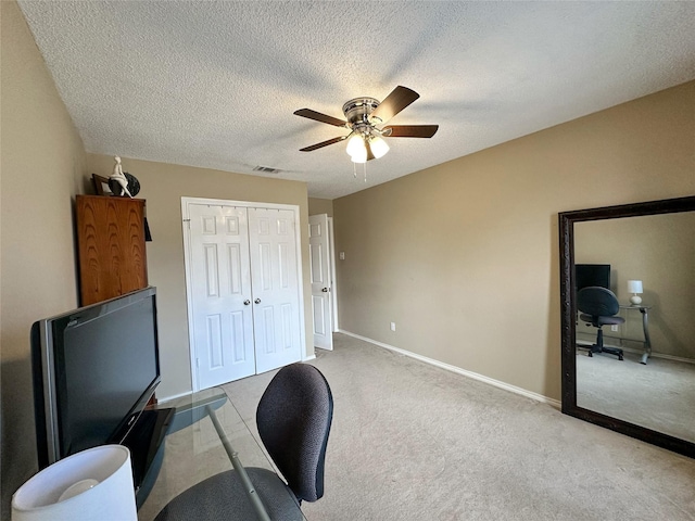 office space with light carpet, a textured ceiling, and ceiling fan