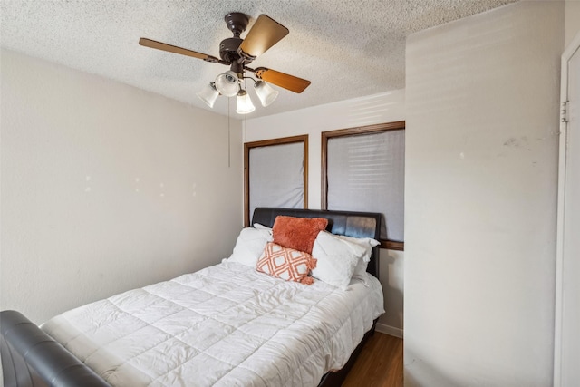 bedroom featuring ceiling fan, dark hardwood / wood-style floors, and a textured ceiling