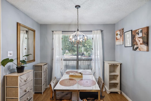 dining area featuring an inviting chandelier, a textured ceiling, and hardwood / wood-style flooring