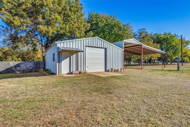 view of outdoor structure with an outbuilding, driveway, and fence