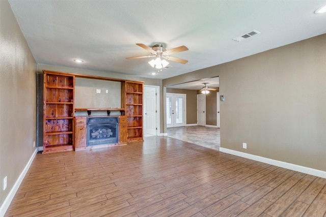 unfurnished living room featuring ceiling fan, french doors, and light hardwood / wood-style flooring