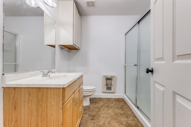 bathroom featuring toilet, heating unit, an enclosed shower, and vanity