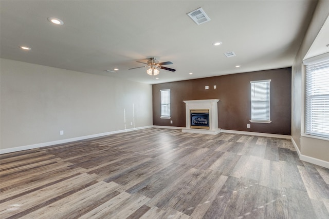 unfurnished living room with ceiling fan, wood-type flooring, and plenty of natural light