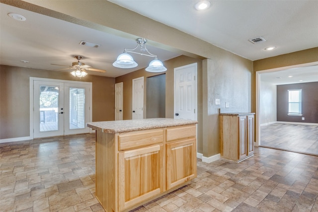 kitchen with ceiling fan with notable chandelier, a kitchen island, decorative light fixtures, french doors, and light brown cabinetry