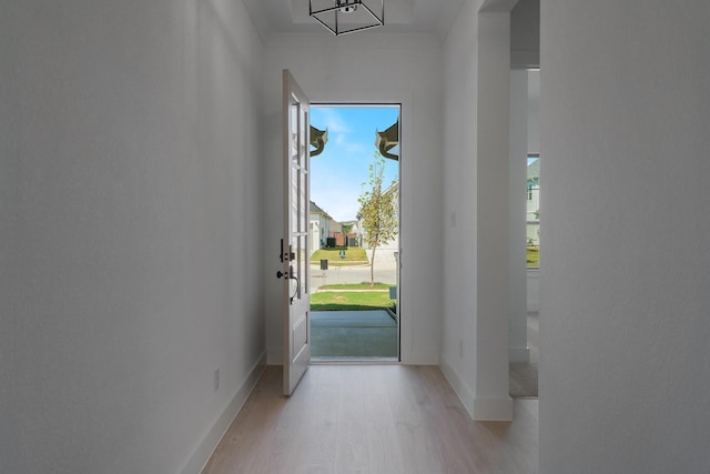 doorway to outside with plenty of natural light, light wood-type flooring, and crown molding