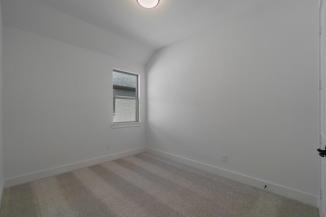 carpeted spare room featuring vaulted ceiling