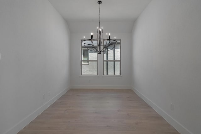 unfurnished dining area featuring lofted ceiling, light hardwood / wood-style flooring, and a notable chandelier