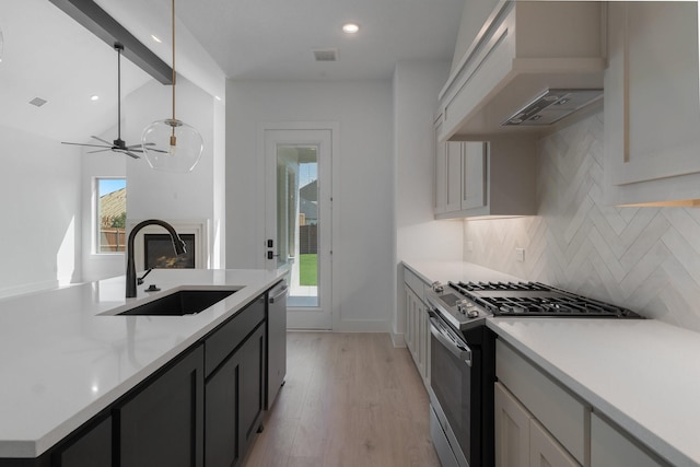 kitchen with sink, stainless steel appliances, premium range hood, backsplash, and pendant lighting