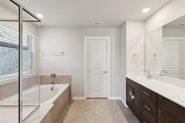 bathroom featuring tile patterned flooring, vanity, and tiled tub