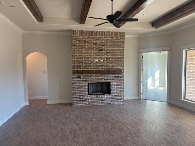 unfurnished living room featuring hardwood / wood-style floors, crown molding, a brick fireplace, ceiling fan, and beam ceiling