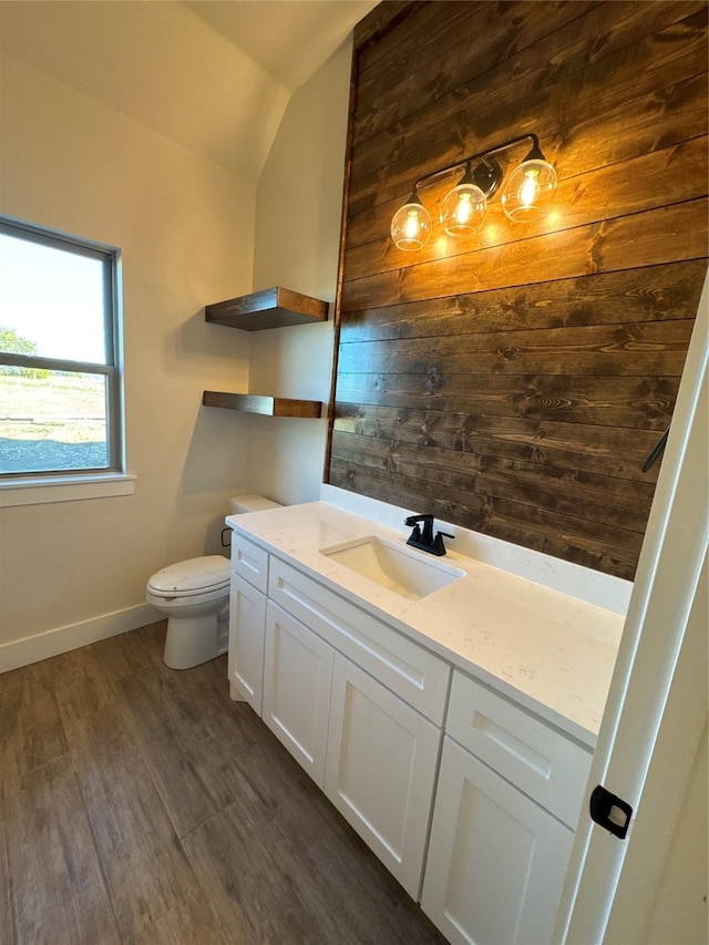 bathroom with toilet, hardwood / wood-style floors, vanity, and vaulted ceiling