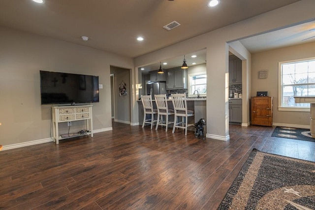 living room with plenty of natural light and dark wood-type flooring