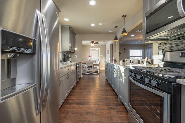 kitchen featuring decorative light fixtures, gray cabinets, light stone countertops, and appliances with stainless steel finishes