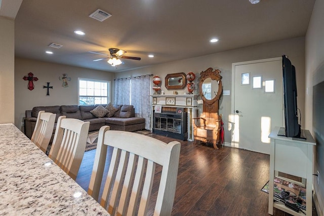 living room with ceiling fan, dark hardwood / wood-style floors, and a brick fireplace