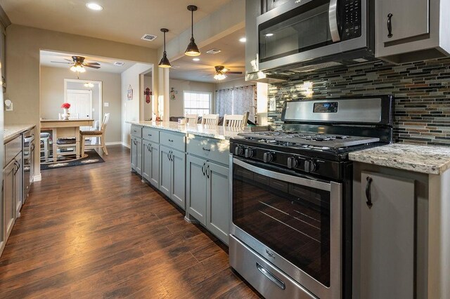 kitchen featuring gray cabinetry, dishwasher, dark wood-type flooring, tasteful backsplash, and light stone counters