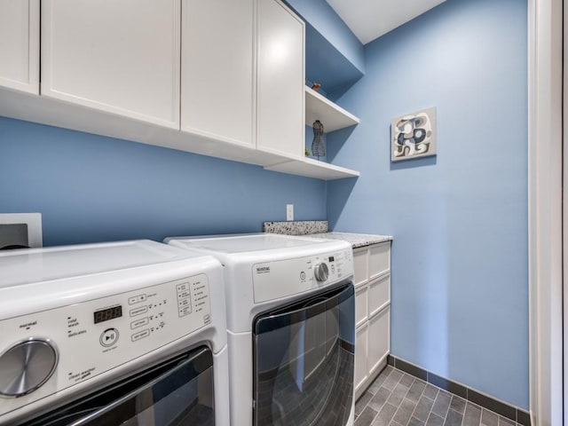 washroom with washing machine and dryer, cabinet space, and baseboards