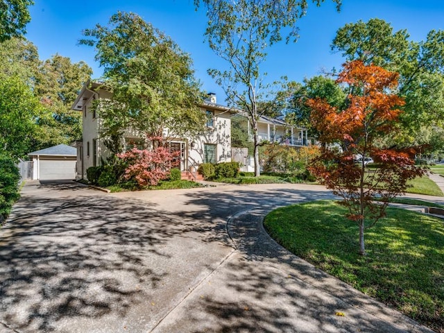 view of front of home with a front lawn, an outdoor structure, and a detached garage