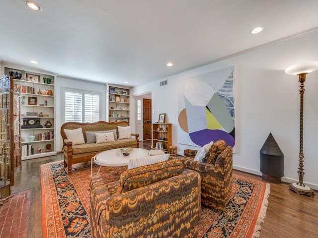 living room with built in shelves, wood-type flooring, and ornamental molding