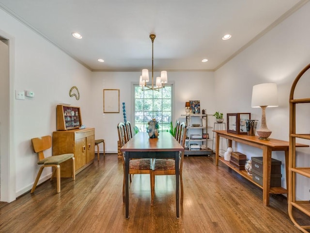 dining area with a chandelier, ornamental molding, and wood finished floors