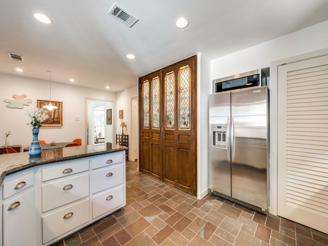 kitchen featuring pendant lighting, visible vents, white cabinets, and stainless steel fridge with ice dispenser