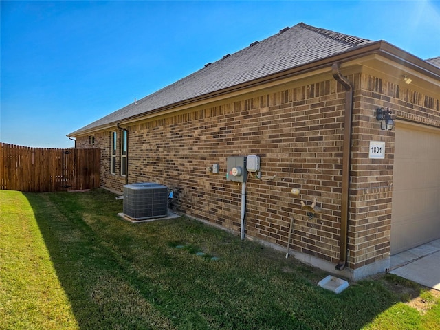 view of side of home featuring a lawn, central AC unit, and a garage