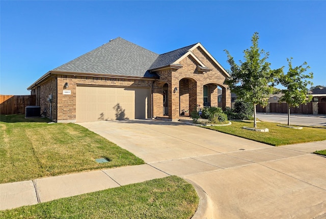 view of front of house featuring a garage, a front lawn, and central air condition unit