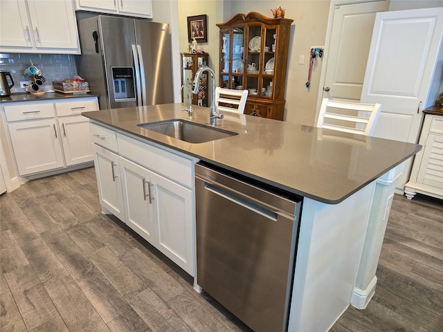 kitchen with dark wood-type flooring, sink, an island with sink, appliances with stainless steel finishes, and white cabinetry