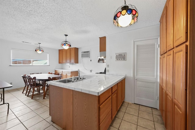 kitchen featuring sink, hanging light fixtures, kitchen peninsula, tile countertops, and light tile patterned floors