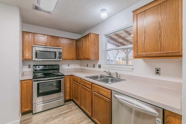 kitchen with sink, stainless steel appliances, and a textured ceiling