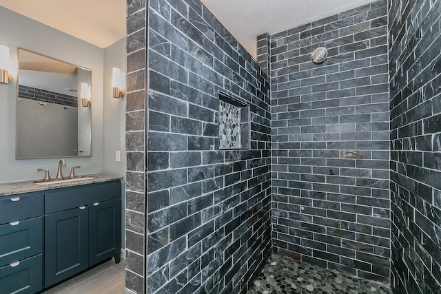 bathroom with tiled shower, a textured ceiling, and vanity